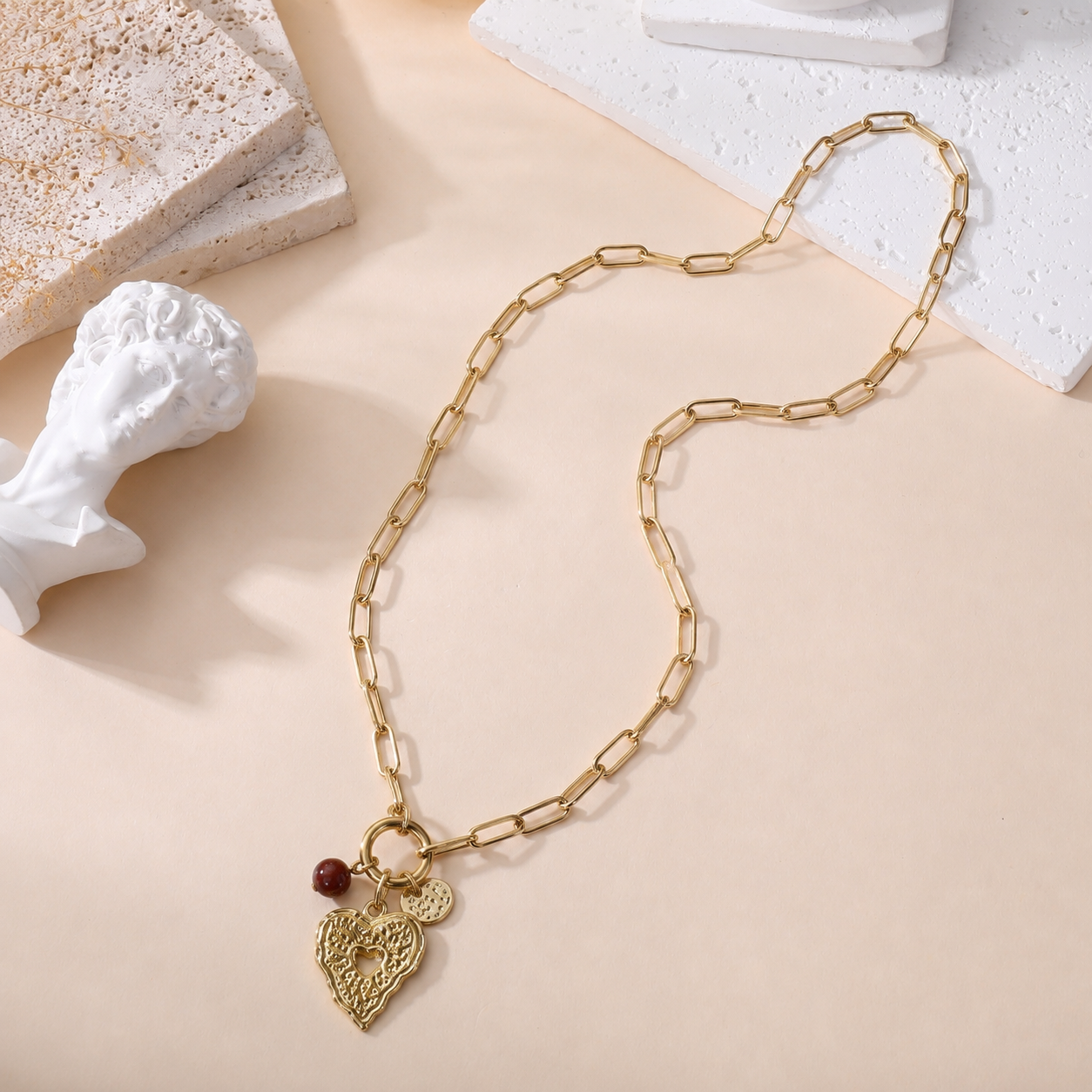 Collier coeur doré chaîne maille rectangulaire avec pendentif coeur texturé et perle bordeaux bijou femme tendance
