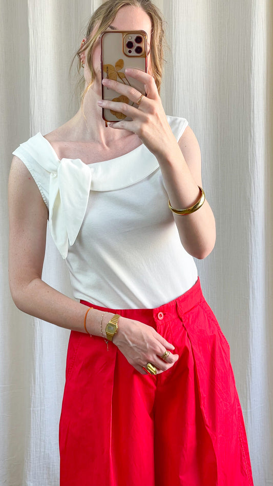 Top blanc asymétrique avec noeud décoratif sur l'épaule porté avec pantalon rouge taille haute femme