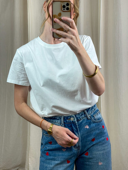 T-shirt blanc col rond coupe classique femme porté avec jean bleu brodé coeurs rouges style casual chic