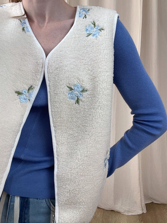 Gilet sans manches sherpa blanc cassé broderies florales bleues style cottage femme porté sur pull bleu