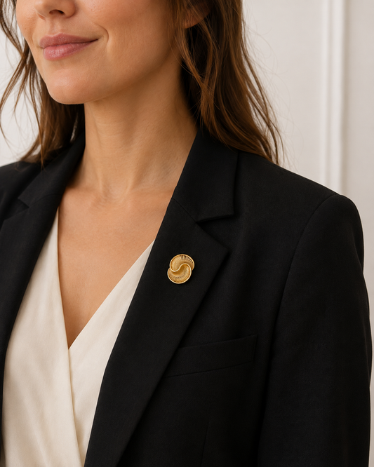 Broche dorée spirale escargot portée sur blazer noir femme, accessoire bijou fantaisie élégant style vintage