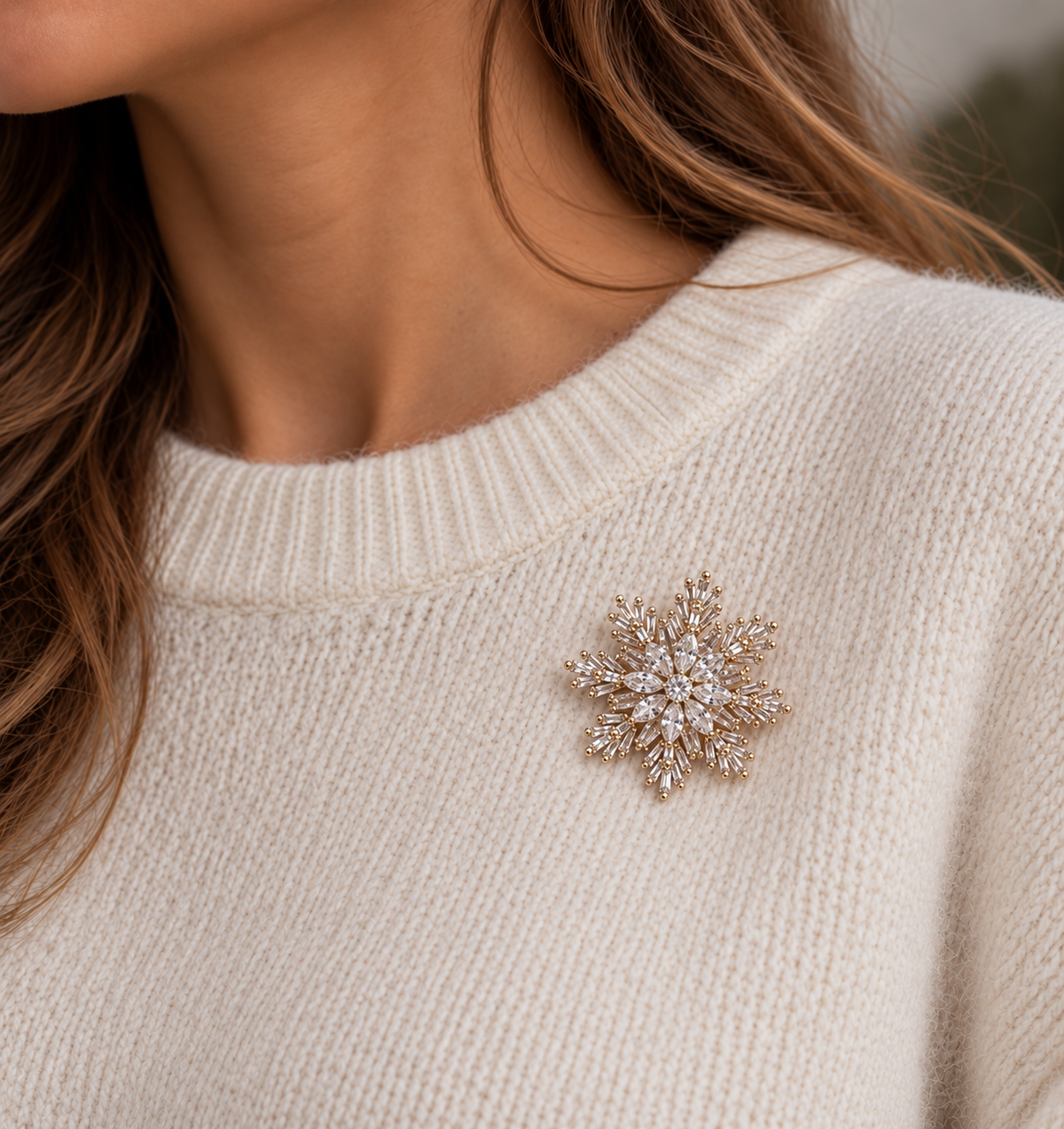 Broche flocon de neige en strass dorés et cristaux blancs portée sur pull beige femme accessoire bijou hiver élégant