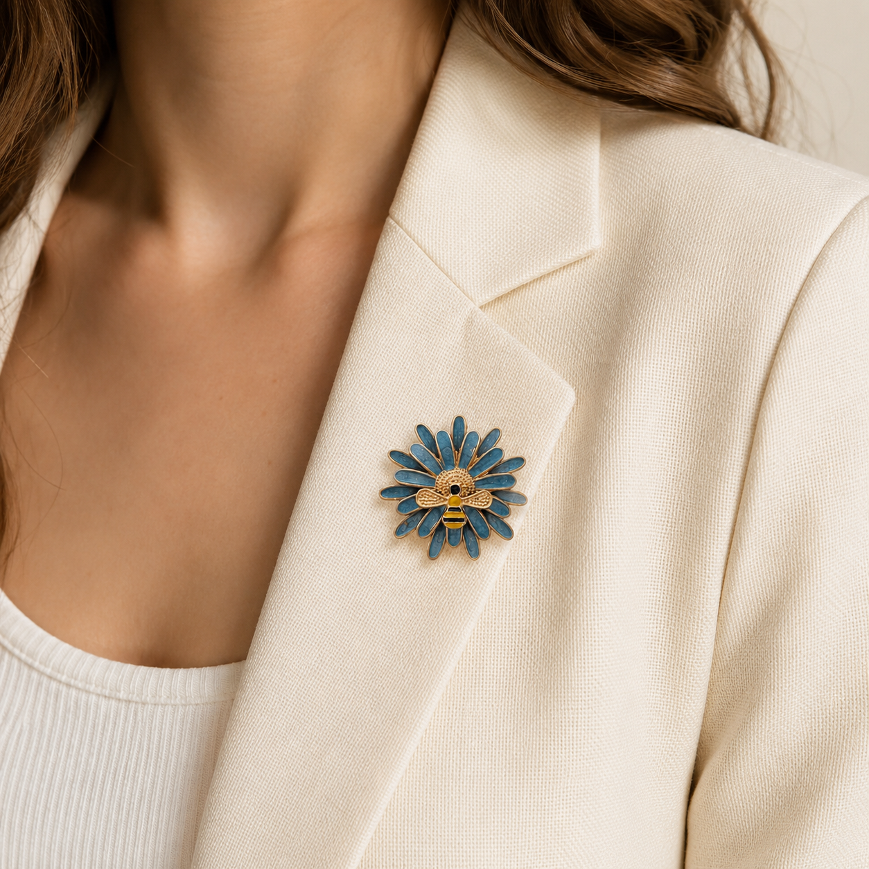 Broche marguerite bleue avec abeille dorée émaillée portée sur blazer crème, accessoire bijou fantaisie femme tendance
