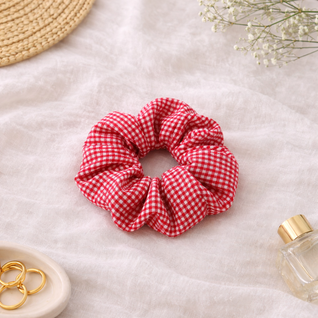 Chouchou rouge à motif vichy blanc posé sur un fond lifestyle doux et lumineux, accessoire cheveux au style romantique