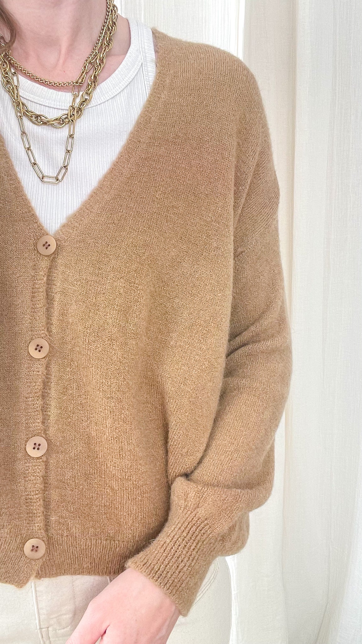 Gilet court camel en baby alpaga boutonné col V porté sur t-shirt blanc avec colliers dorés femme