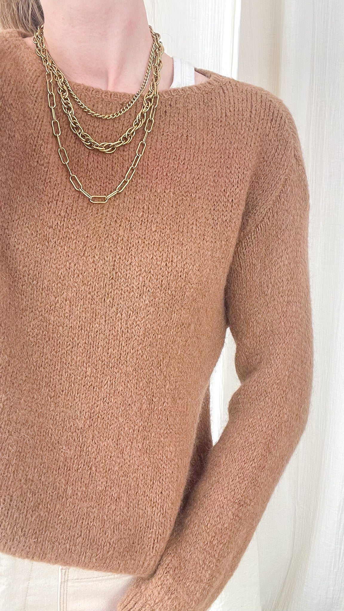 Pull femme marron camel en maille douce col rond, style minimaliste chic porté avec colliers dorés superposés