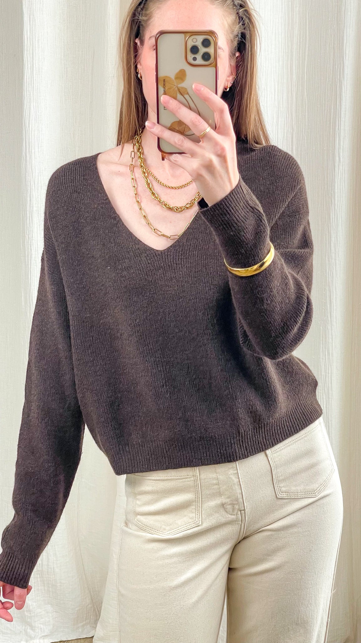 Pull court marron col V femme en maille douce, coupe ample décontractée, porté avec pantalon beige et bijoux dorés
