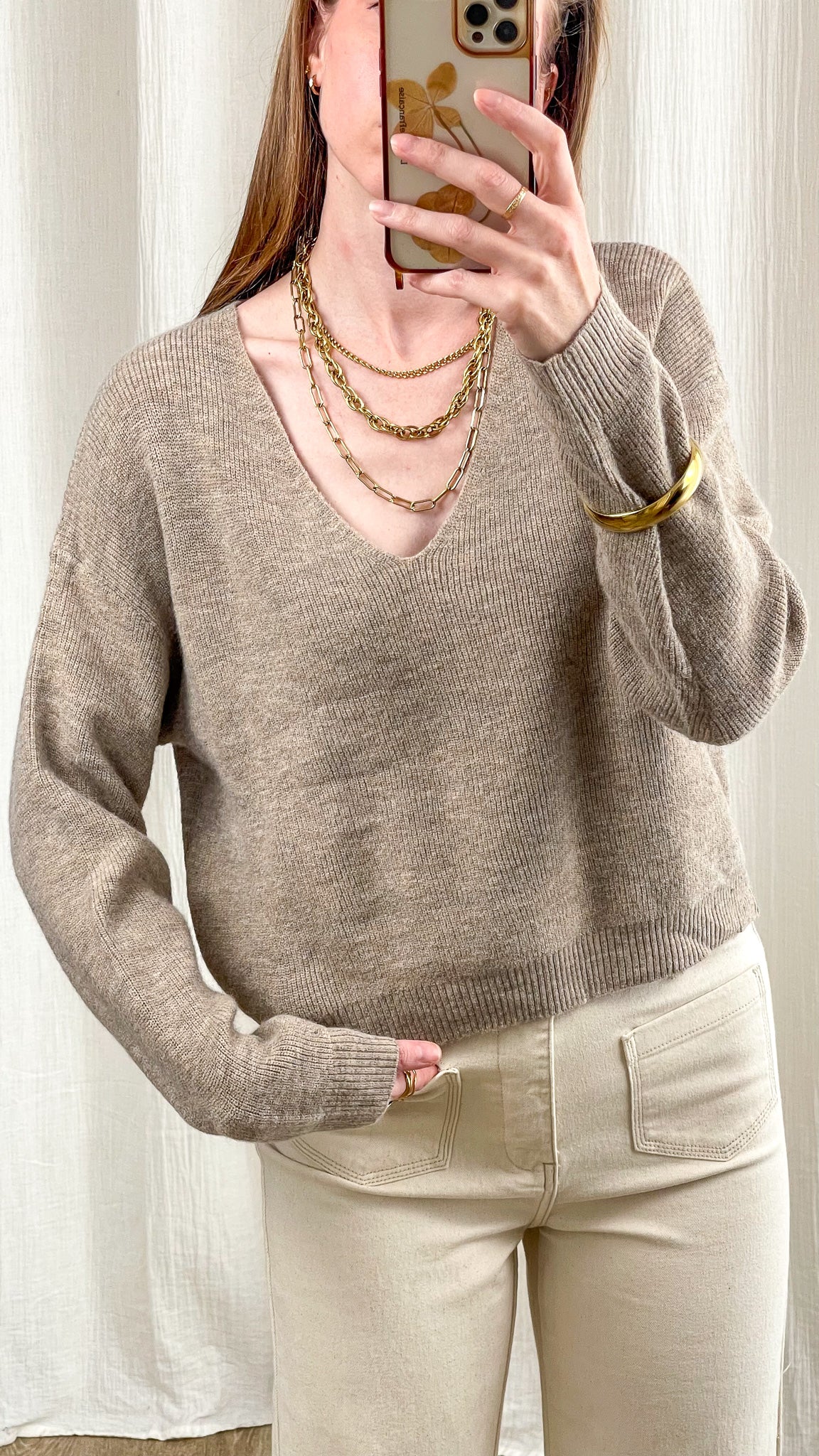 Pull court col V beige taupe maille douce coupe ample femme, porté avec colliers dorés et pantalon écru