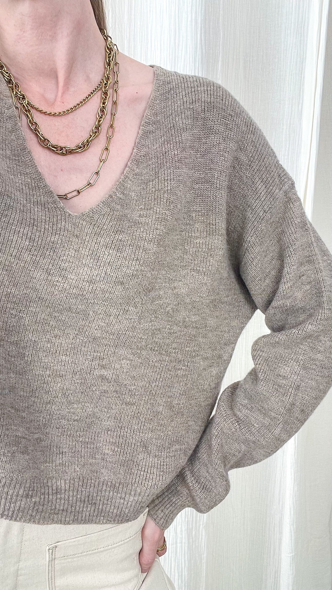 Pull court col V taupe chiné femme, maille douce coupe ample, style minimaliste chic porté avec colliers dorés