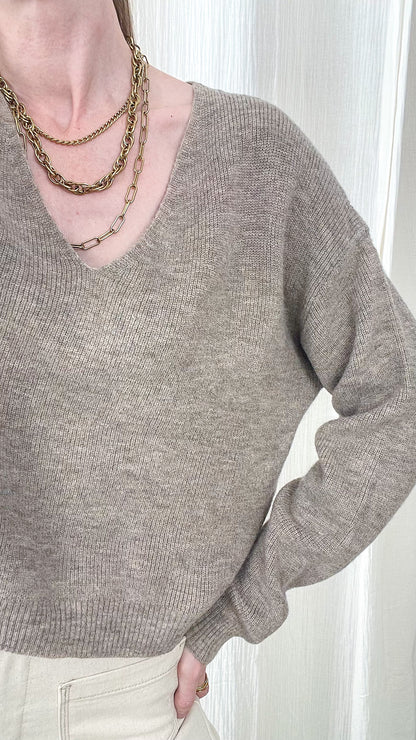 Pull court col V taupe chiné femme, maille douce coupe ample, style minimaliste chic porté avec colliers dorés