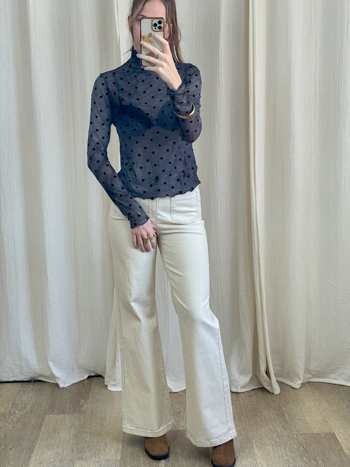 Top mesh bleu marine transparent à pois noirs col montant manches longues porté avec jean blanc flare femme