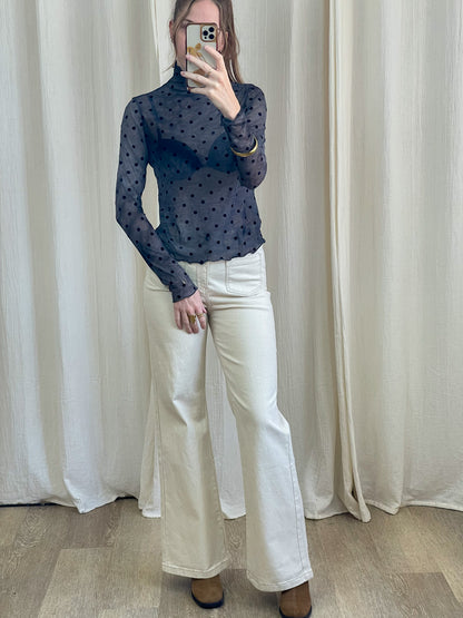Top mesh bleu marine transparent à pois noirs col montant manches longues porté avec jean blanc flare femme