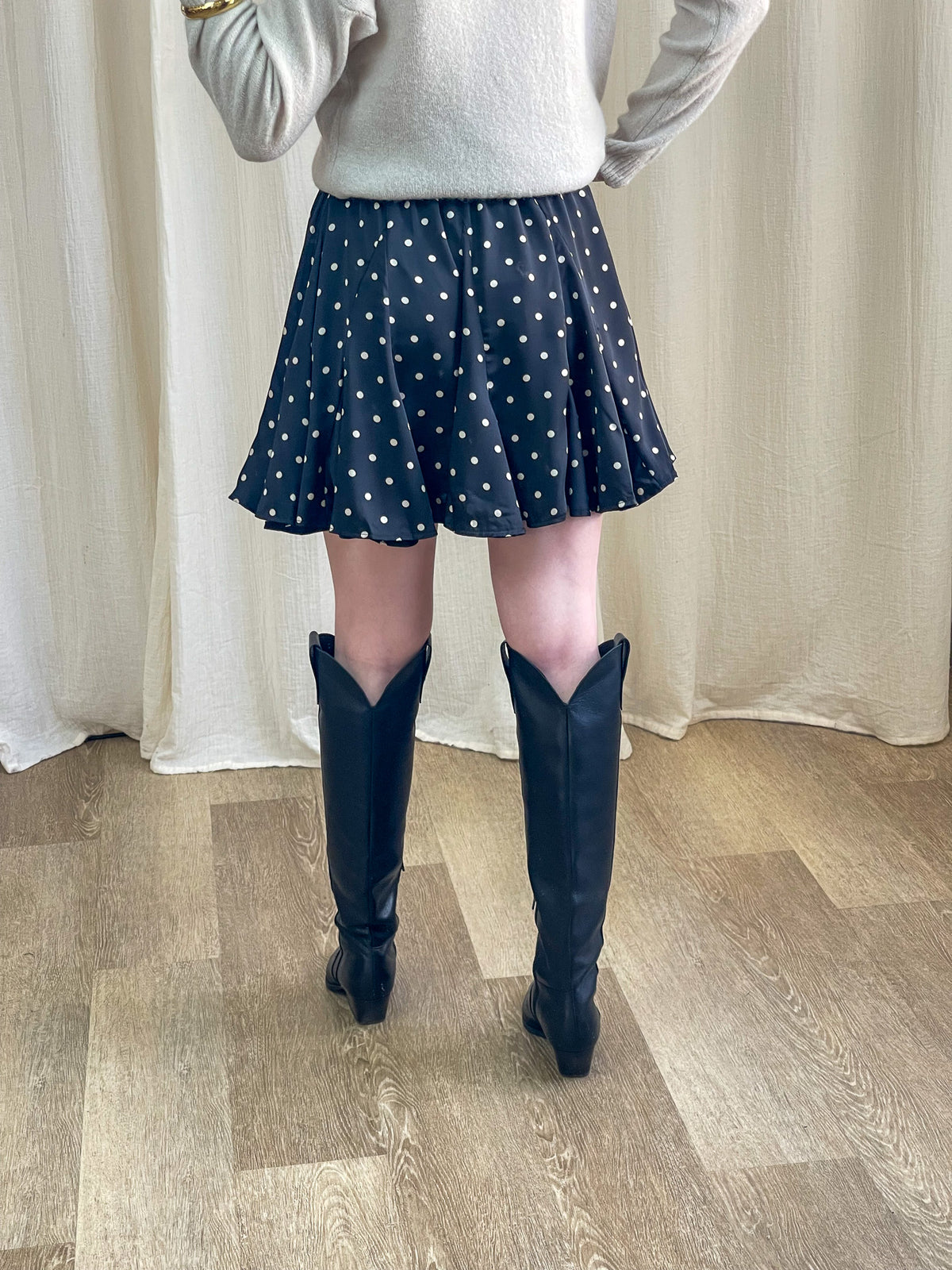 Jupe patineuse à pois noir et blanc femme coupe évasée associée à un pull beige et bottes western noires