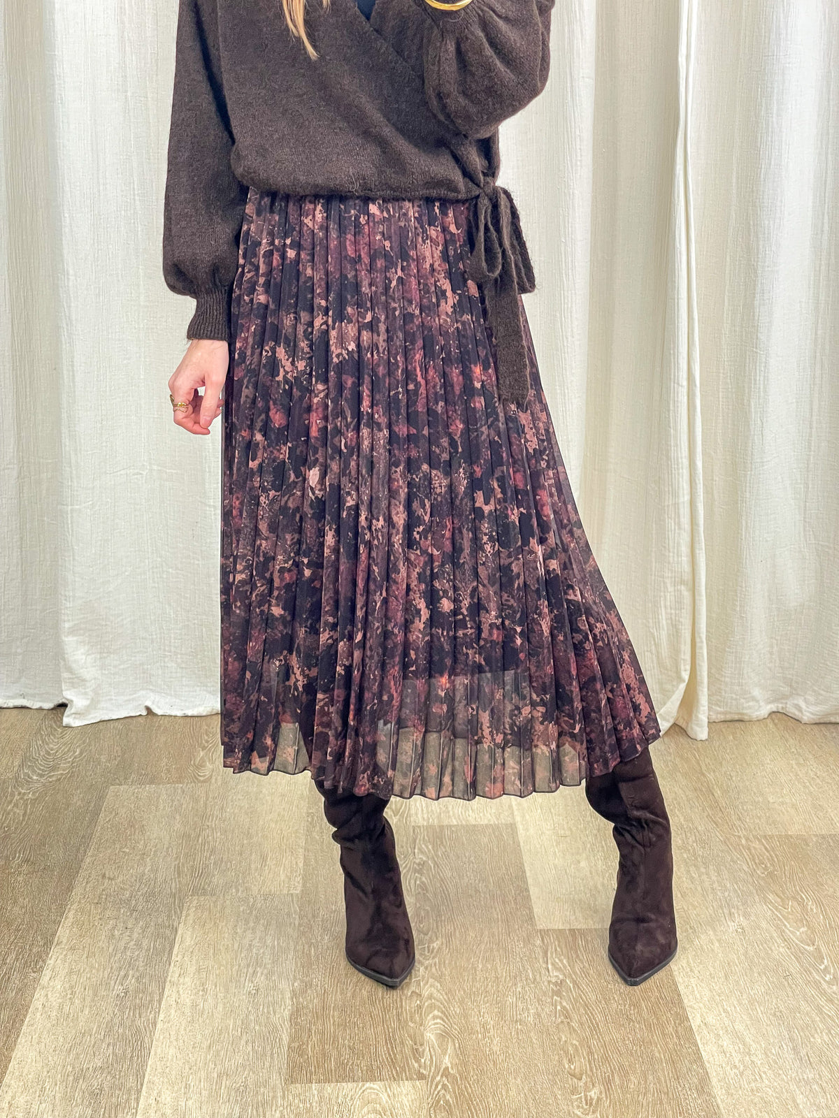 Jupe midi plissée imprimé floral bordeaux et noir femme avec pull cache-cœur marron et bottes hautes