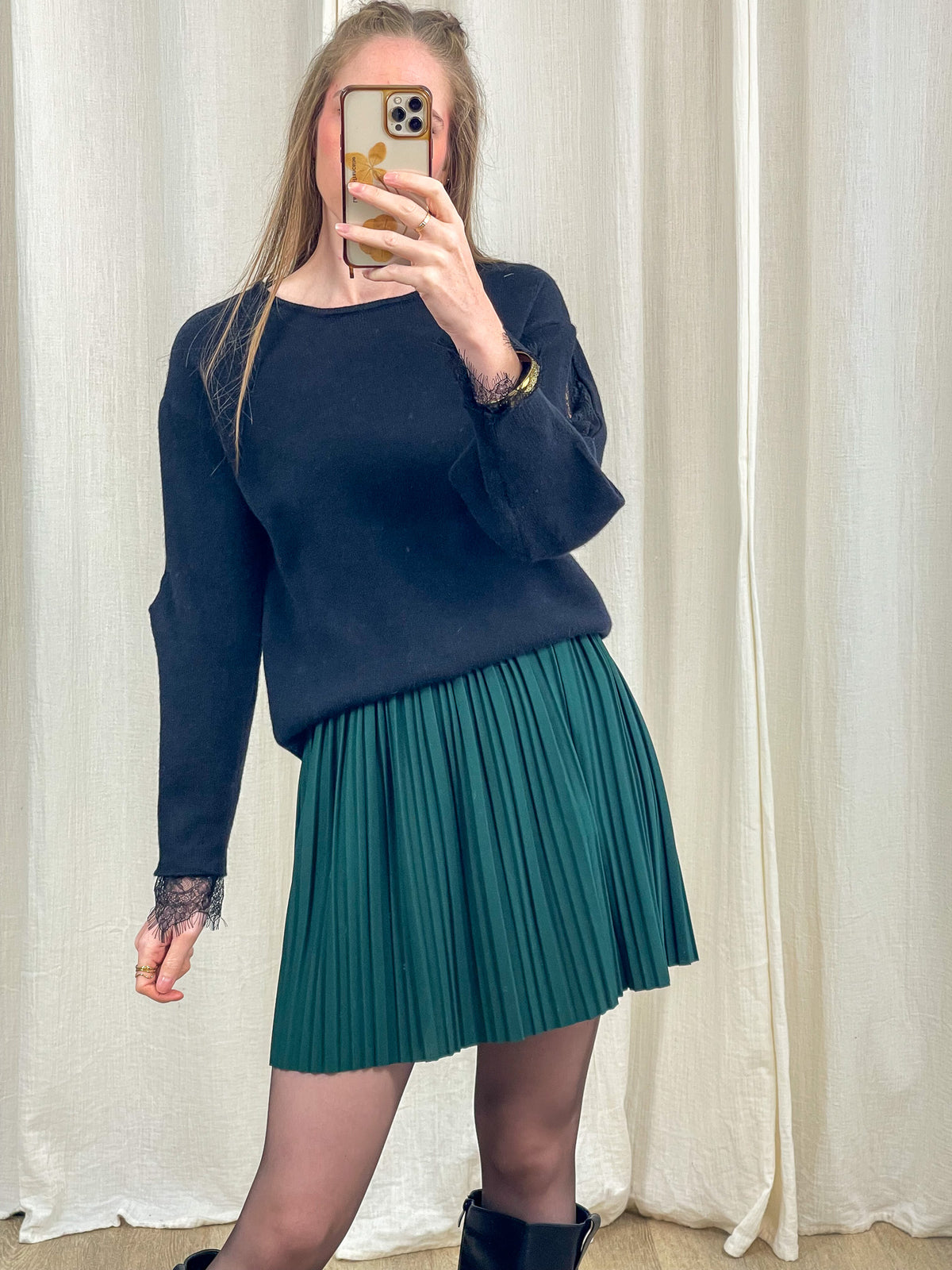 Jupe courte plissée vert sapin taille haute élastique portée avec pull noir, look femme automne hiver