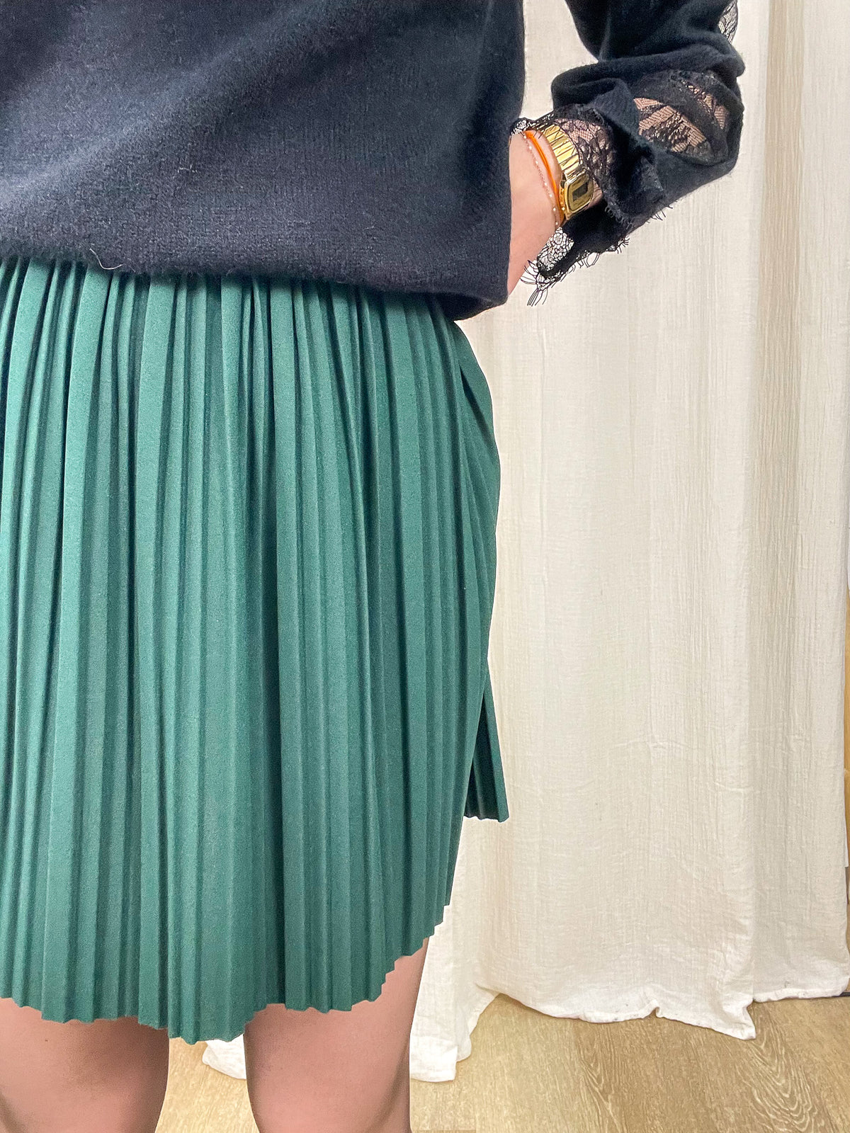 Jupe courte plissée vert émeraude taille haute élastique femme portée avec pull noir détails dentelle