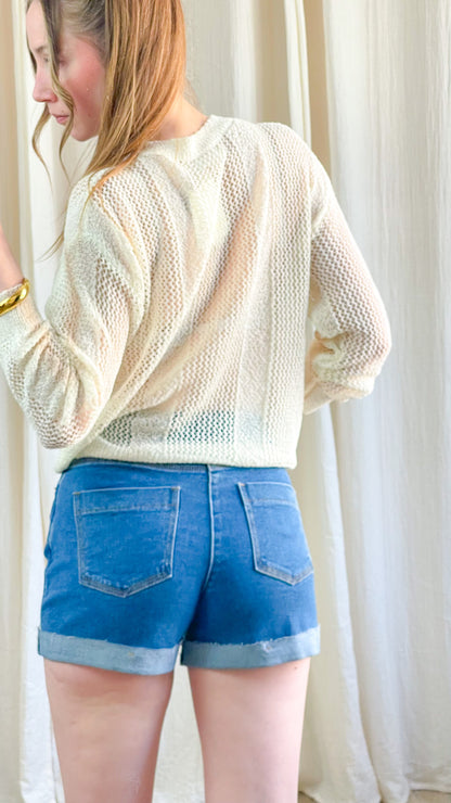 Short en jean bleu femme coupe mom taille haute avec revers, porté avec pull en maille écru, style casual chic été