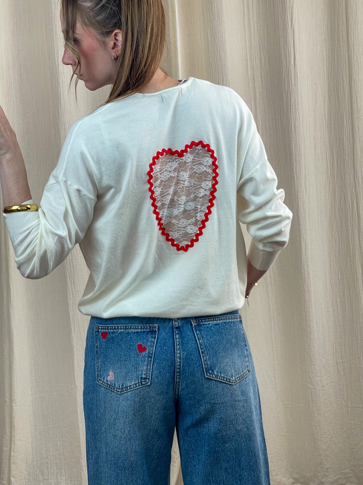 Pull femme blanc cassé avec dos ajouré cœur en dentelle bordure rouge style romantique porté avec jean taille haute