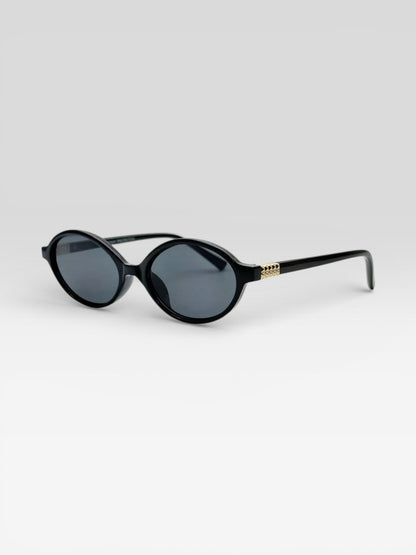 Lunettes de soleil ovales noires rétro femme avec détail chaîne dorée sur branches style vintage chic