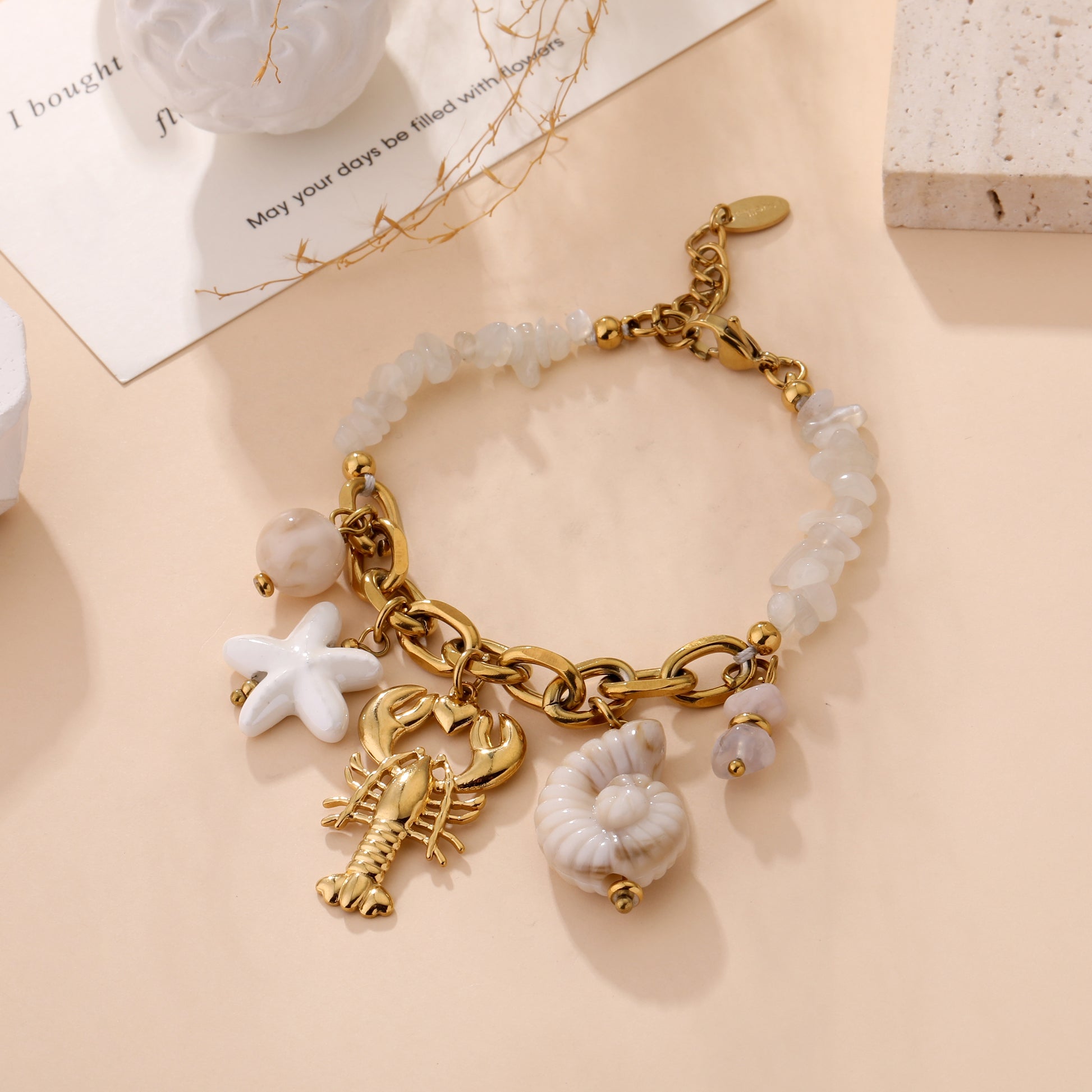 Bracelet Assya doré avec breloques marines homard étoile de mer et perles nacrées blanches bijou femme tendance été