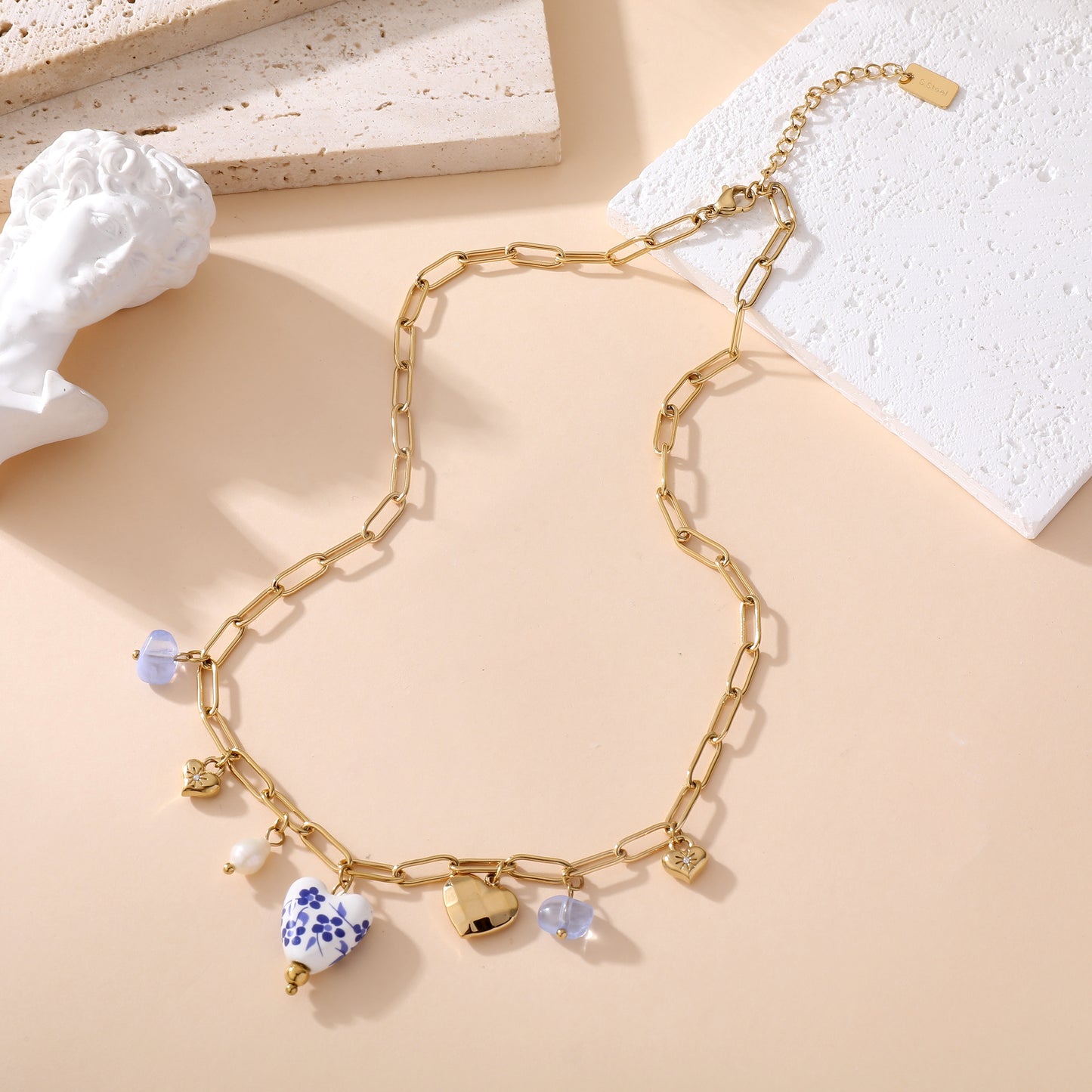 Collier chaîne dorée maille rectangle avec pendentifs cœurs céramique blanc bleu floral et perles femme style bohème chic