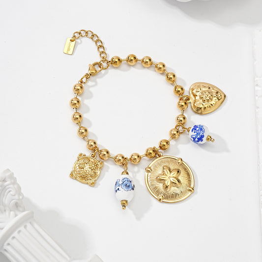 Bracelet à breloques doré avec perles rondes, médaillons fleuris et perles céramique bleu blanc style bohème chic femme