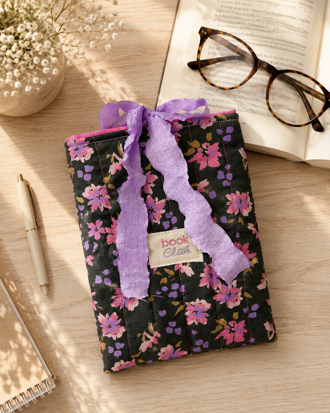 Pochette livre matelassée motif floral violet et rose sur fond noir avec ruban lavande, étui protection book club femme