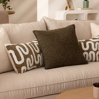Coussin bouclette kaki Soana 45x45 cm avec motifs abstraits blancs sur canapé beige décoration intérieure moderne