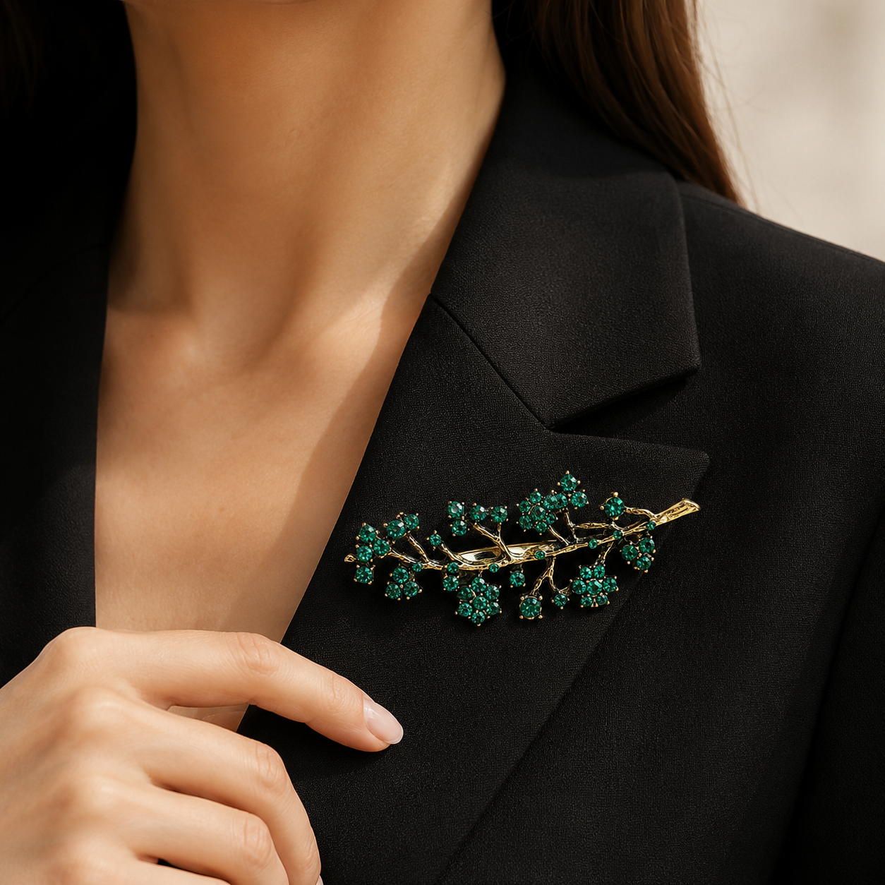 Broche branche dorée avec fleurs en cristaux verts émeraude portée sur blazer noir femme élégant
