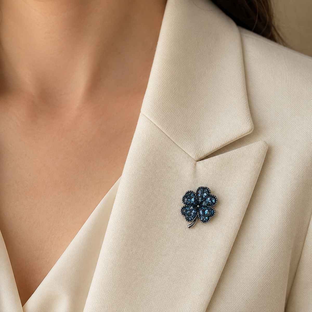 Broche trèfle quatre feuilles cristaux bleu marine portée sur blazer beige femme, épinglette porte-bonheur élégante