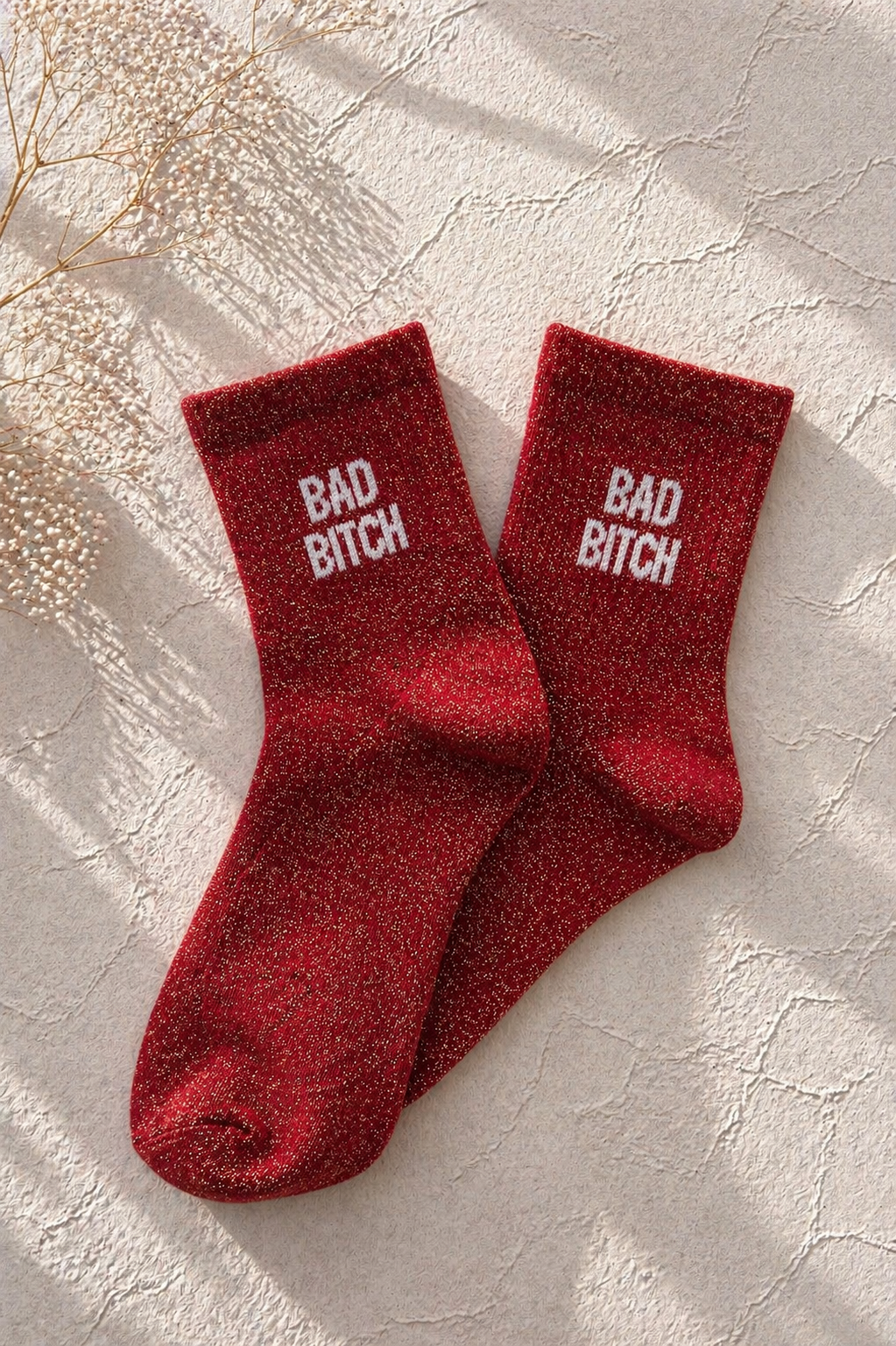 Chaussettes pailletées rouge avec inscription BAD BITCH brodée en blanc sur fond clair texturé