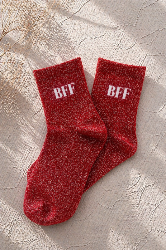 Chaussettes pailletées rouges avec inscription BFF brodée en blanc sur fond clair texturé