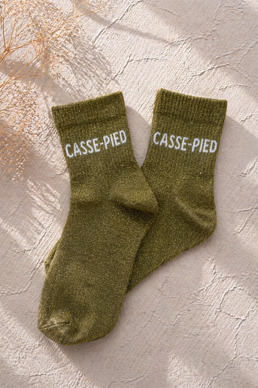 Chaussettes pailletées kaki avec inscription CASSE-PIED brodée en blanc sur fond clair texturé