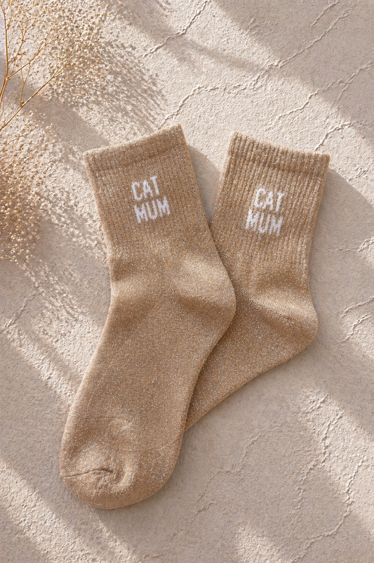 Chaussettes pailletées beige avec inscription CAT MUM brodée en blanc sur fond clair texturé