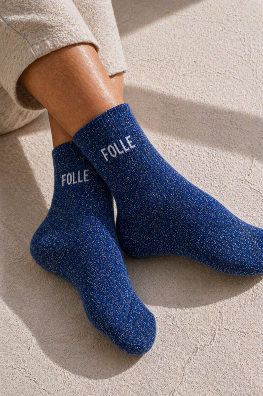 Chaussettes pailletées bleu FOLLE portées, effet scintillant avec inscription blanche visible sur la cheville