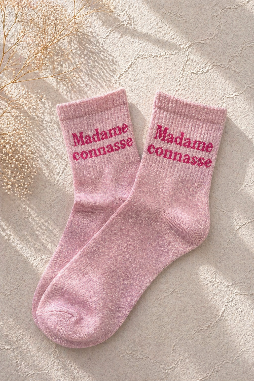 Chaussettes pailletées rose avec inscription Madame connasse brodée en rose fuchsia sur fond clair texturé