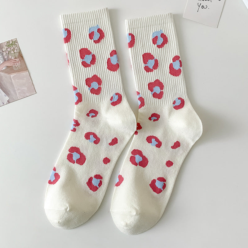 Chaussettes femme blanches à motif léopard coloré rouge et bleu posées à plat sur fond clair