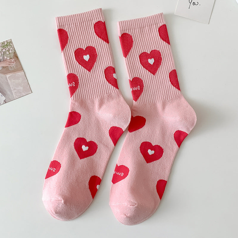 Chaussettes femme roses à motifs cœurs rouges posées à plat sur fond clair
