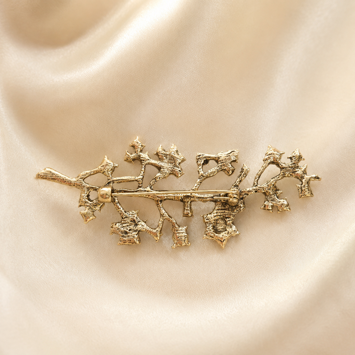 Broche dorée motif branche de houx texturé style vintage accessoire femme élégant