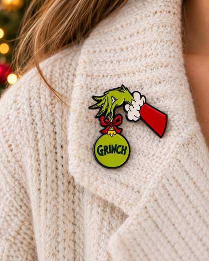 Pin's Grinch Noël vert main tenant boule de sapin rouge épingle fantaisie accessoire fêtes femme