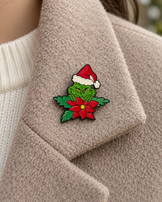 Pin's Grinch Noël vert avec bonnet rouge et poinsettia, broche émaillée fantaisie sapin fêtes sur manteau beige