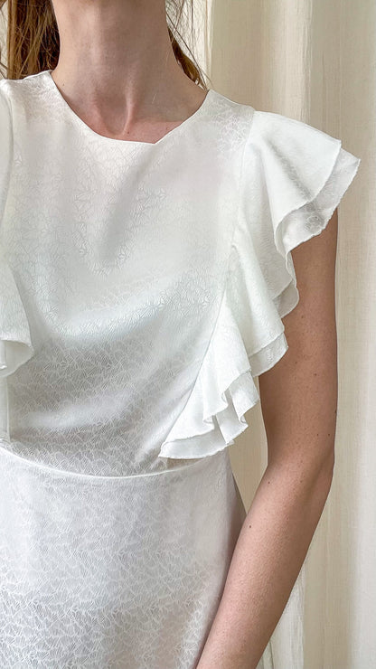 Détail robe Begonia blanche avec volants sur les épaules tissu satiné texturé