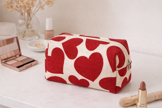 Trousse en velours écru avec motifs cœurs rouges posée sur une table en fond lifestyle